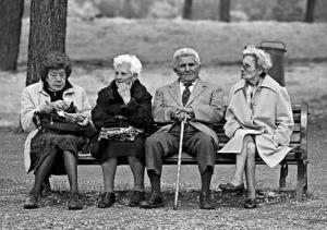 quattro vecchi seduti su una panchina in un parco, foto in bianco e nero