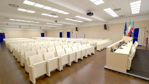 Auditorium con poltrone fisse e tavolo relatori